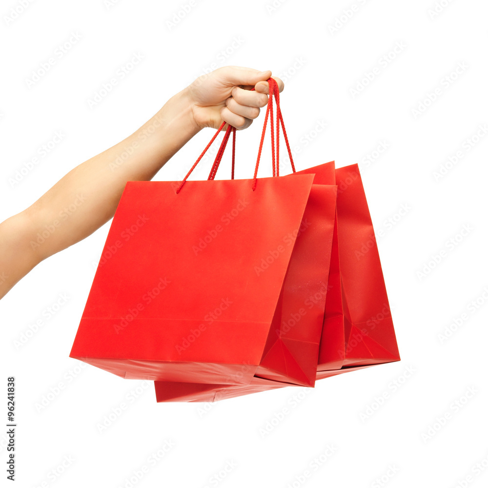 close up of hand holding red shopping bags