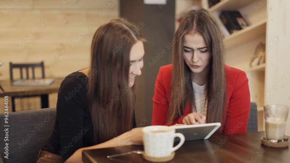 Two happy girlfriends with tablet smile in cafe Two happy girlfriends with tablet smile in cafe