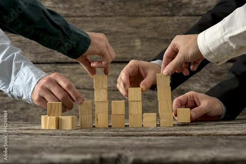 Hands of five businessman holding wooden blocks placing them int photo