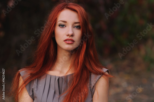 Fototapeta Outdoors portrait of beautiful young woman with red hair
