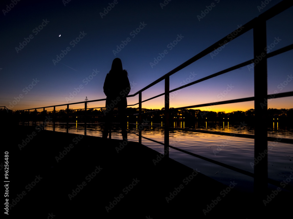 mujer a contraluz / puesta de sol en lago