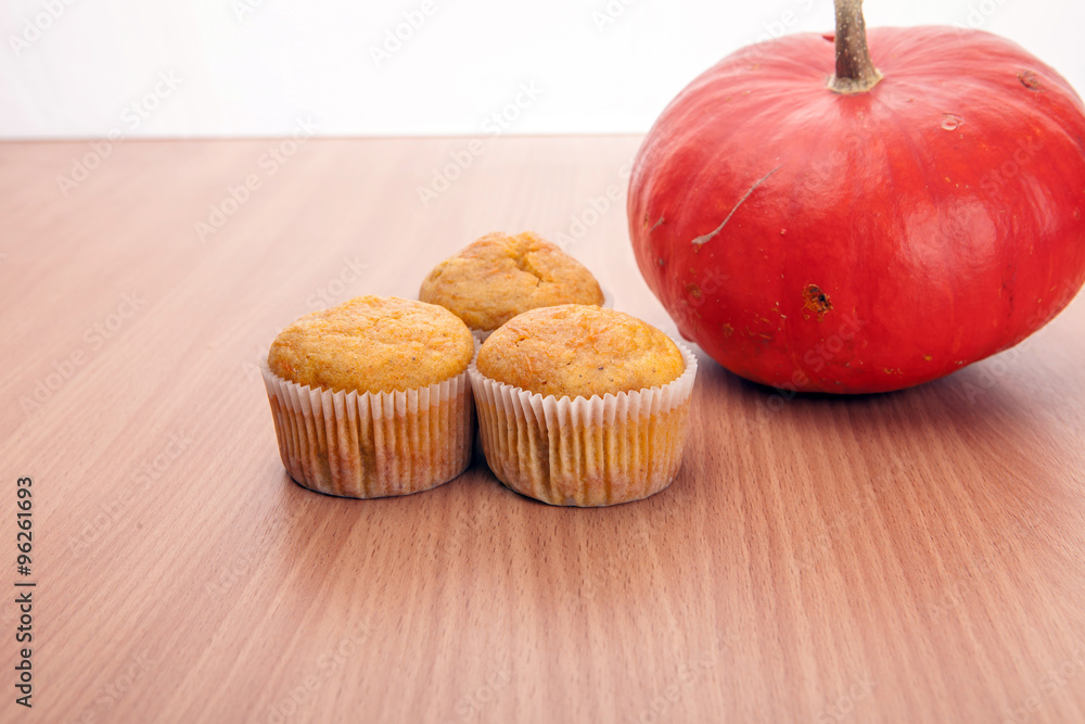 Three cupcakes and pumpkin on wood texture table Three cupcakes and pumpkin on wood texture table