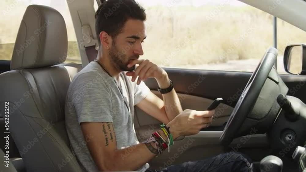 hispanic man sitting in car texting hispanic man sitting in car texting