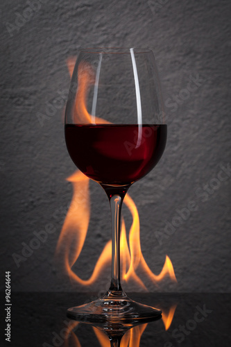 Glass. Red wine glass  with fire splash in front of stone granit