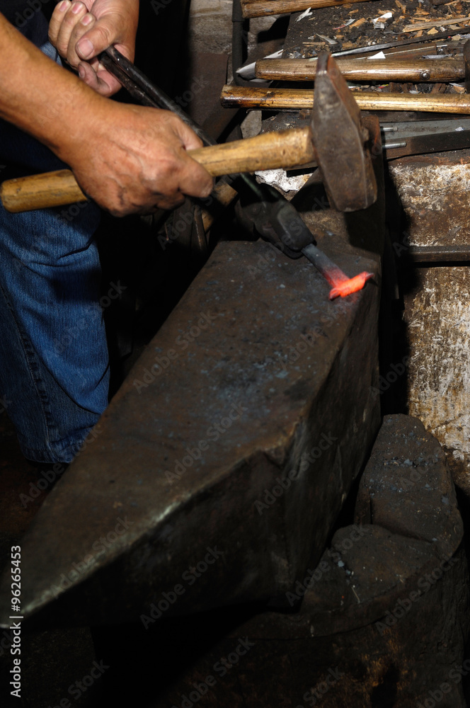 Blacksmith forges iron in the forge