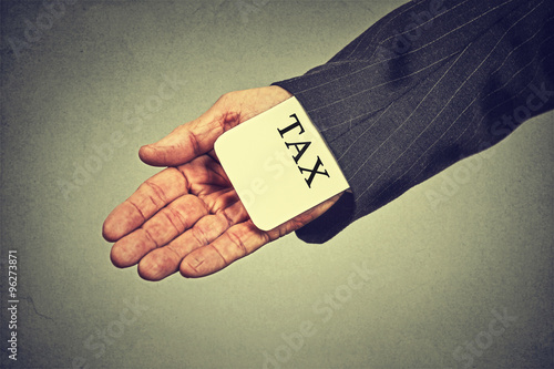 man hand hiding tax card in a sleeve of a suit. tax evasion economy concept photo