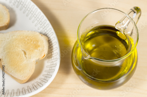 Crystal cruet with Extra Virgin olive oil beside a dish with toasted slces of bread. Mediterranean breakfast