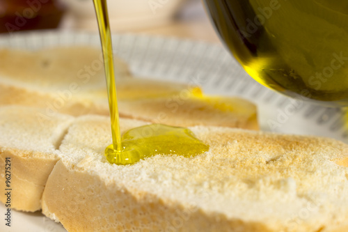 Pouring Extra Virgin olive oil on a slice of toasted bread. Mediterranean breakfast photo