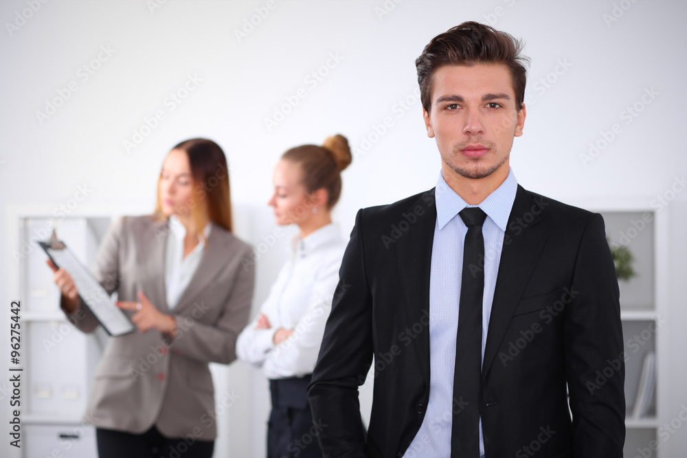 Cheerful business man in office with colleagues in the background, sturt up team Cheerful business man in office with colleagues in the background, sturt up team