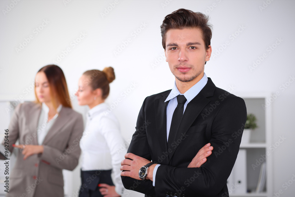 Cheerful business man in office with colleagues in the background, sturt up team Cheerful business man in office with colleagues in the background, sturt up team