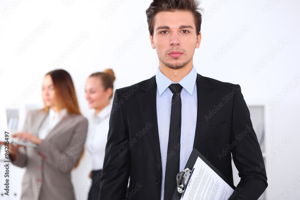 Cheerful business man in office with colleagues in the background, sturt up team Cheerful business man in office with colleagues in the background, sturt up team