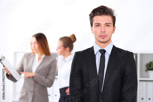 Cheerful business man in office with colleagues in the background, sturt up team