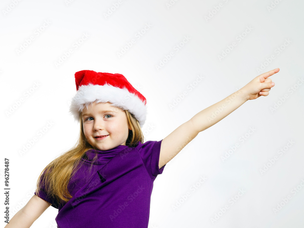 Cute little girl in santa red hat showing by hand Cute little girl in santa red hat showing by hand