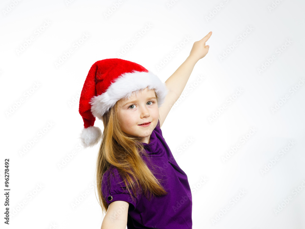 Cute little girl in santa red hat showing by hand Cute little girl in santa red hat showing by hand