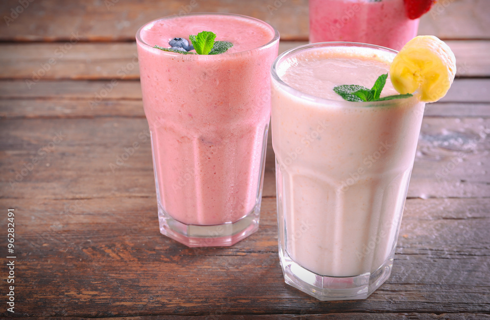 Glasses of fresh cold smoothie with fruit and berries, on wooden background Glasses of fresh cold smoothie with fruit and berries, on wooden background