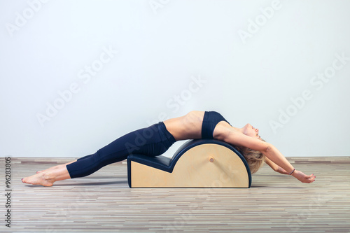 Pilates, fitness, sport, training and people concept -  woman doing  exercises on small barrel