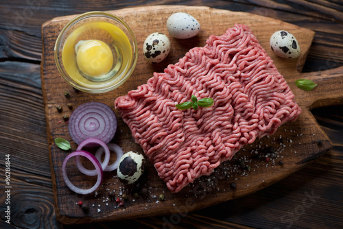 Top view of raw ground beef meat with seasonings, studio shot