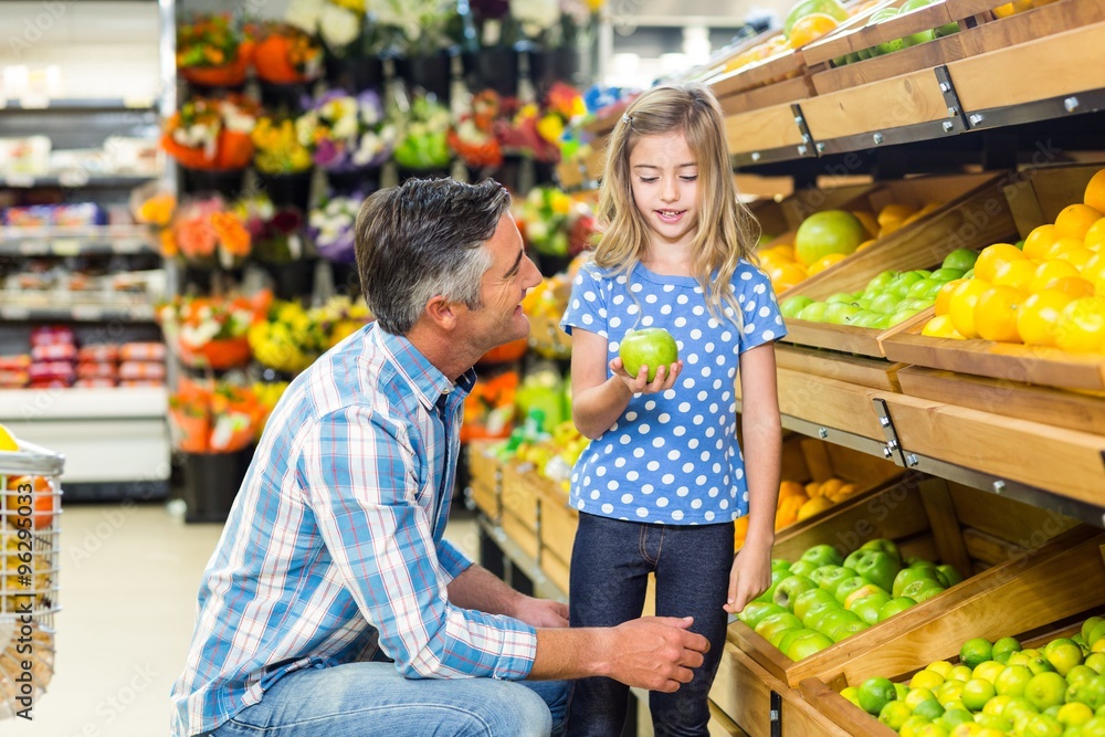 Cute child holding a green apple in the grocery shop