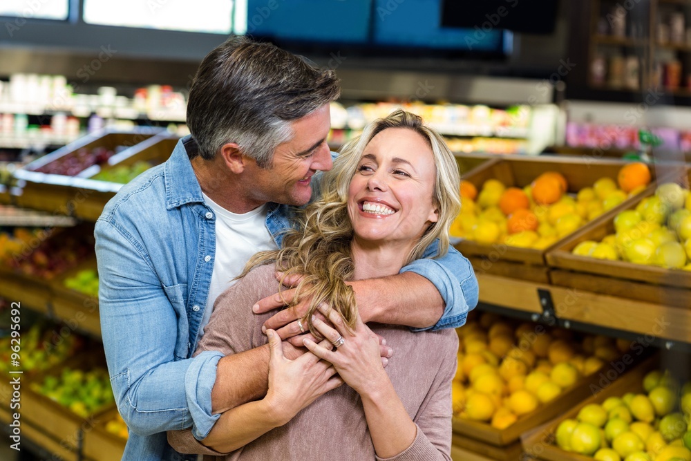 Smiling couple hugging in fruit aisle 