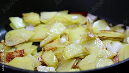 Closeup of rustic natural cut potatoes, frying in a pan.  photo