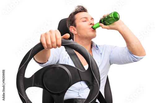 Young irresponsible man driving and drinking a beer