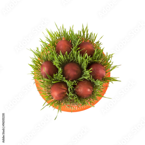 Red easter eggs in green grass isolated on white.