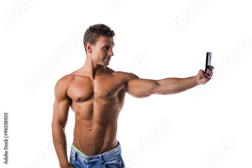 Handsome muscular young man taking selfie with cell phone