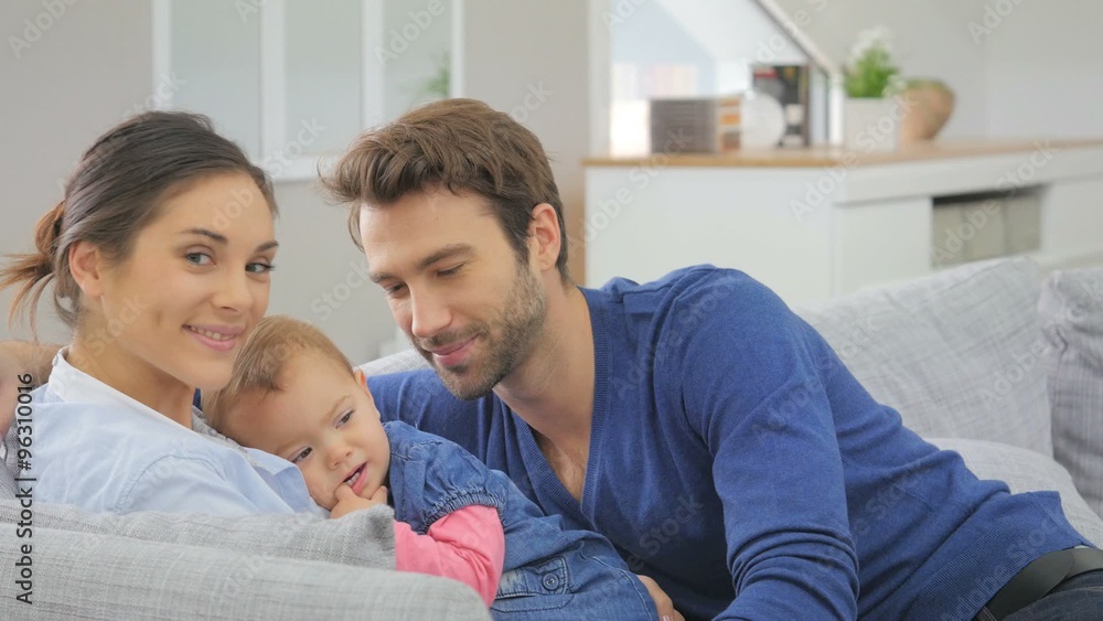 Young parents with baby sitting in sofa at home Young parents with baby sitting in sofa at home