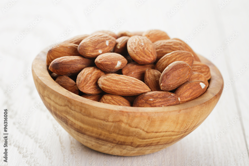 olive bowl full of almonds on wood table olive bowl full of almonds on wood table