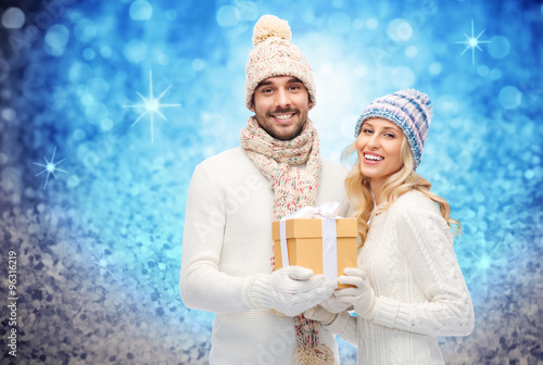 smiling couple in winter clothes with gift box