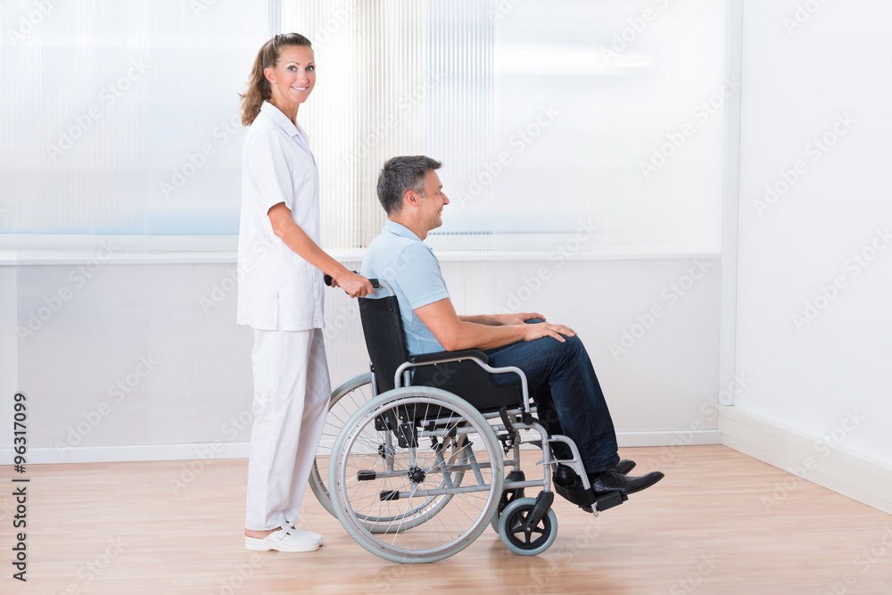 Doctor Pushing Disabled Patient On The Wheelchair Doctor Pushing Disabled Patient On The Wheelchair