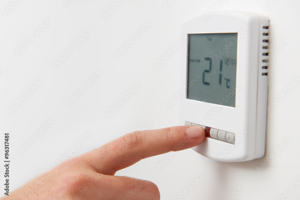 Close Up Of Hand Adjusting Digital Central Heating Thermostat Co Close Up Of Hand Adjusting Digital Central Heating Thermostat Co