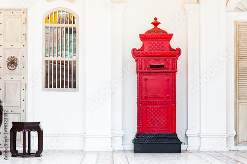 red and vintage postbox in front of an old building