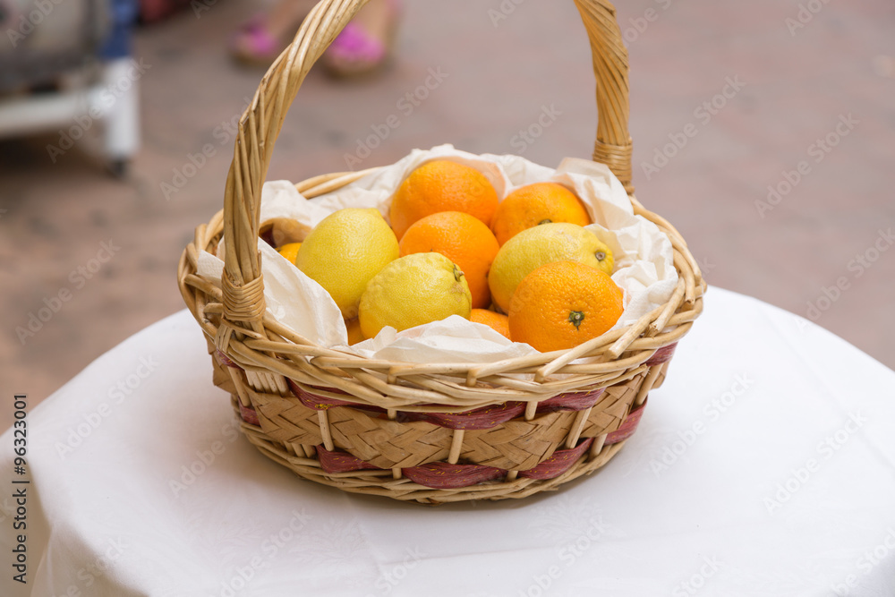 citrus fruits in a basket on a table in the street during the day. lemons and oranges in a basket made of twigs