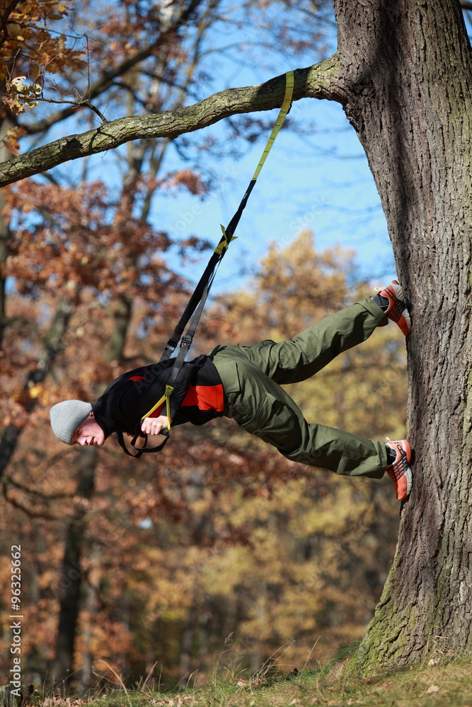outdoor suspension training in forest - caucasian man at tree outdoor suspension training in forest - caucasian man at tree