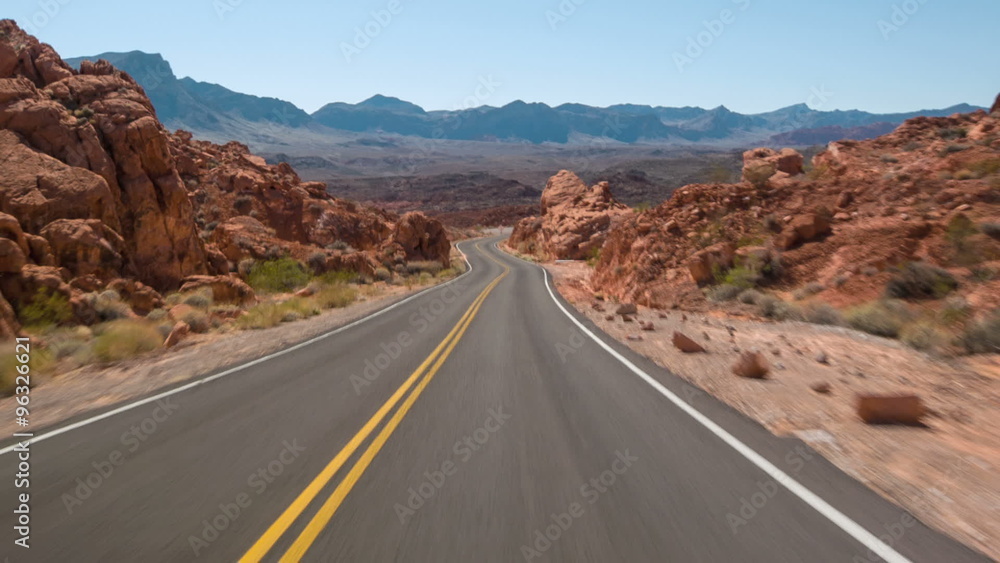 Driving USA: spectacular red rocks and mountains car point of view on lonely empty highway road in Valley of Fire, Nevada desert
