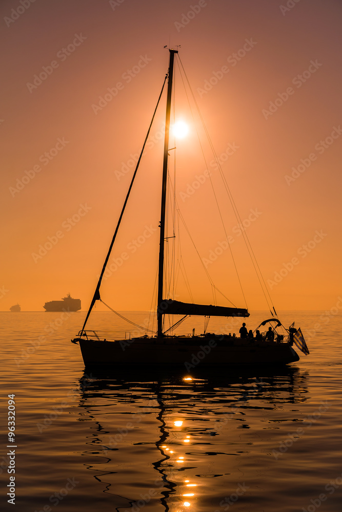 Sailing boat before sunset time, in tranquil sea water