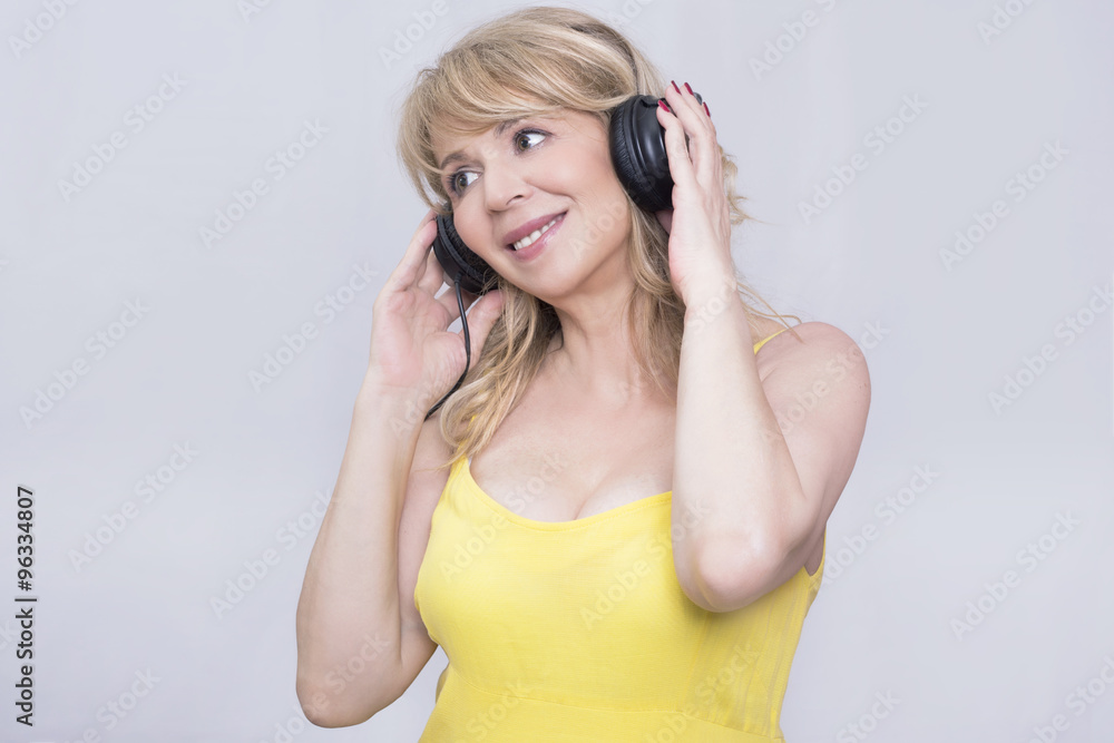 Naklejka premium Blonde woman listening to music on headphones 