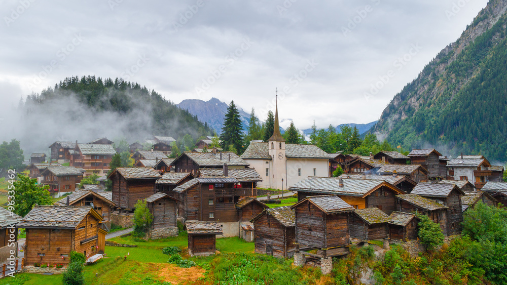  Belalp village in fog. Wooden houses and buildings in old style, vintage. Switzerland