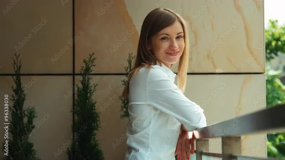 Portrait of a young adult woman standing on a balcony. Looking and smiling at camera Portrait of a young adult woman standing on a balcony. Looking and smiling at camera