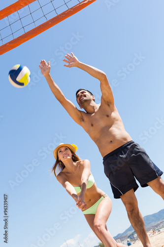 Girl and guy playing volleyball at beach