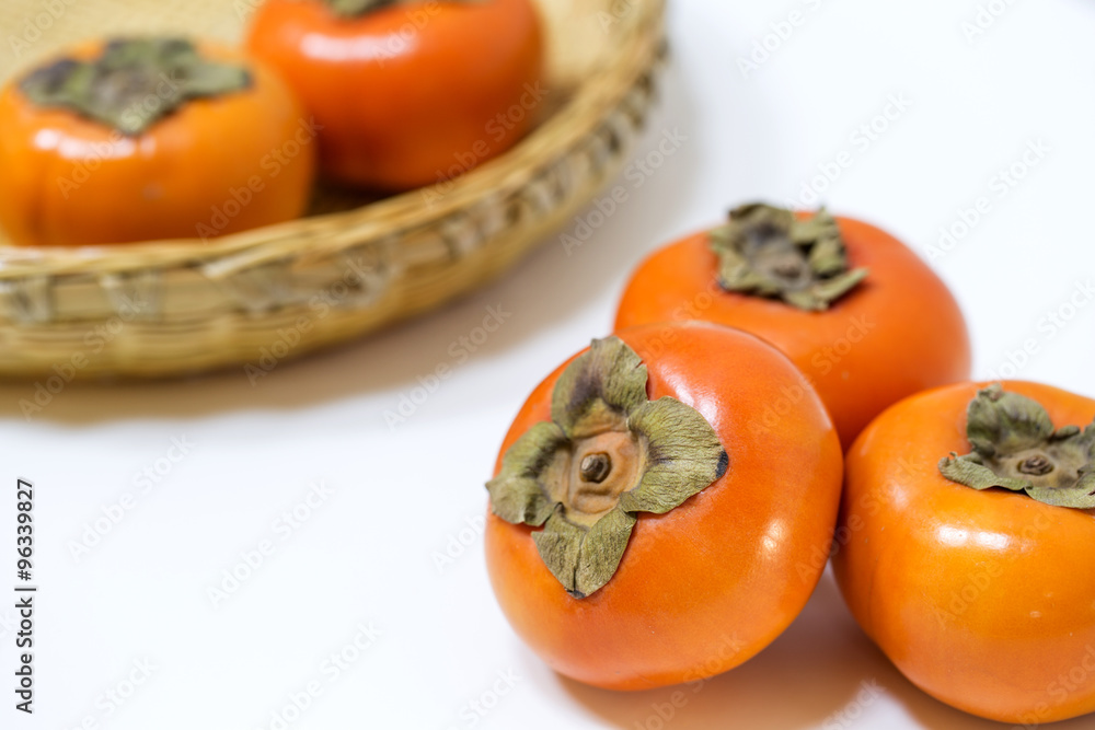 Fresh ripe persimmons on Japanese bamboo basket Fresh ripe persimmons on Japanese bamboo basket