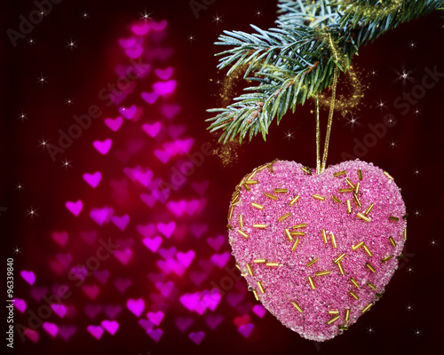 Christmas decorations in the form of heart on fir branch with a background of hearts