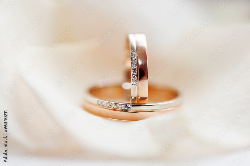 Golden wedding rings with diamonds lie on silk fabric. Symbol of love and marriage. Golden wedding rings with diamonds lie on silk fabric. Symbol of love and marriage.
