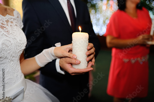 Wedding candles in the hands of the newlyweds