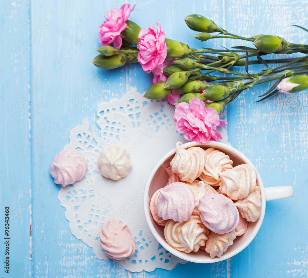 Meringues and pink flowers on the table, top view Meringues and pink flowers on the table, top view