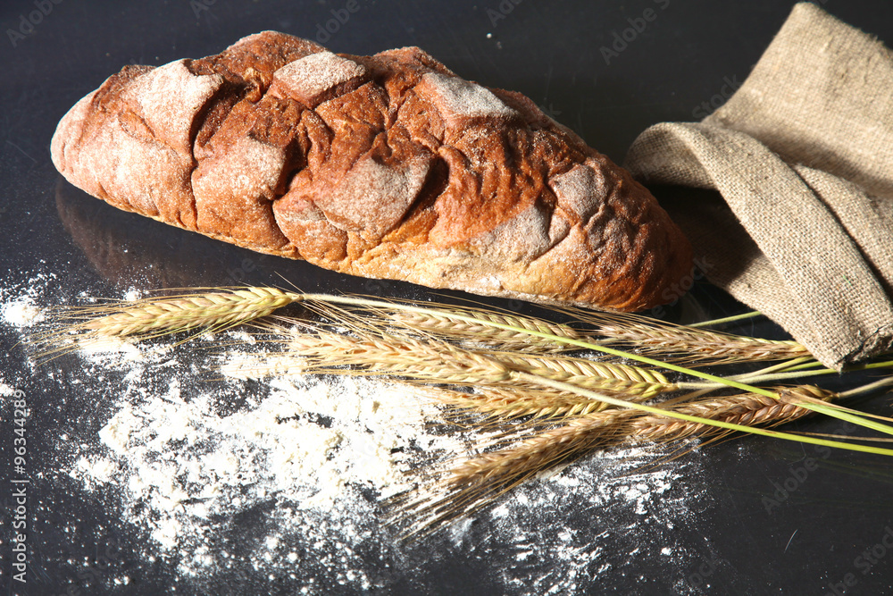 rustic crusty bread and wheat ears on a dark wooden table Stock Photo ...