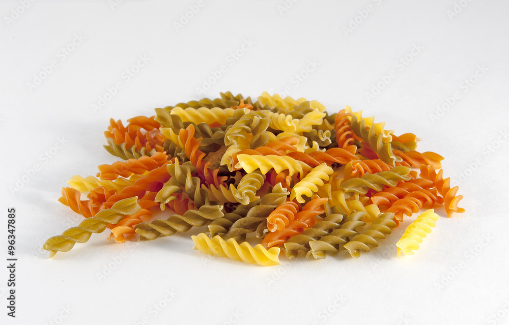 Fototapeta premium Uncooked coloured Rotini Pasta against a white background