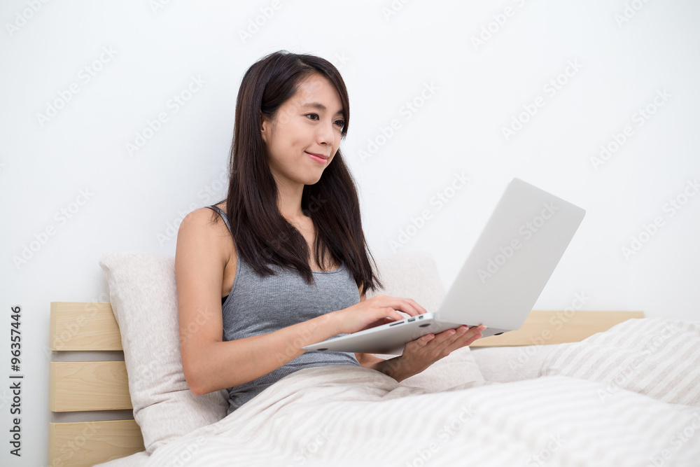 Young Asian woman using the laptop computer and sitting in bed Young Asian woman using the laptop computer and sitting in bed