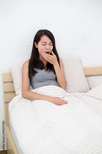 Woman yawning in bed, after waking up